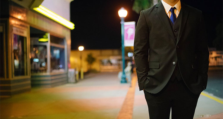 夜の街に立っているスーツの男性